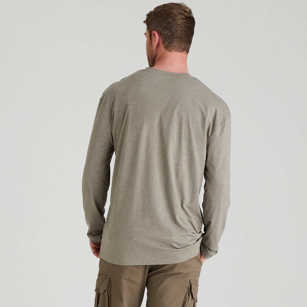 back view of man wearing a grey long-sleeve shirt and cargo pants on a light grey background