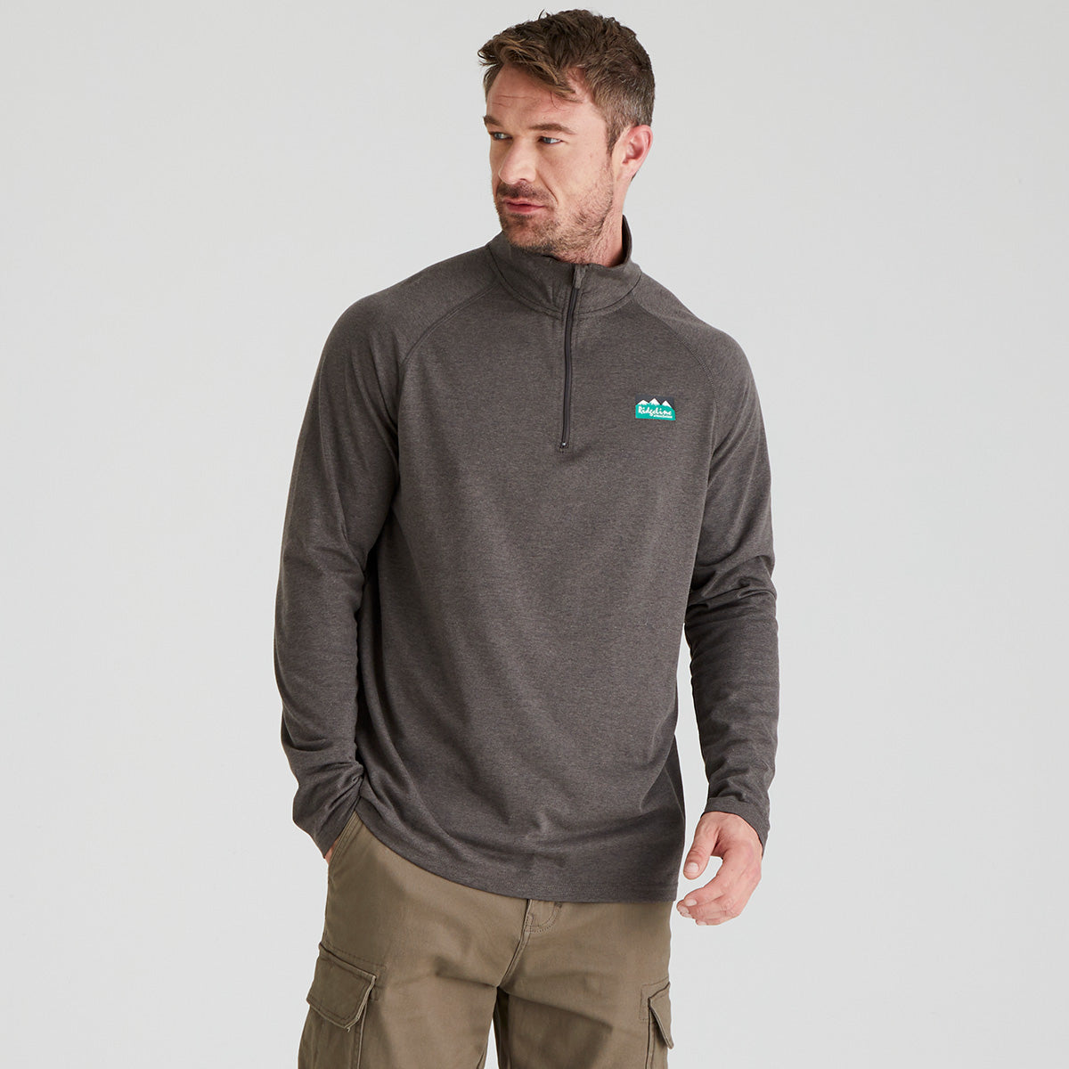 Man wearing a grey pullover with a Ridgeline Clothing logo on a light grey background