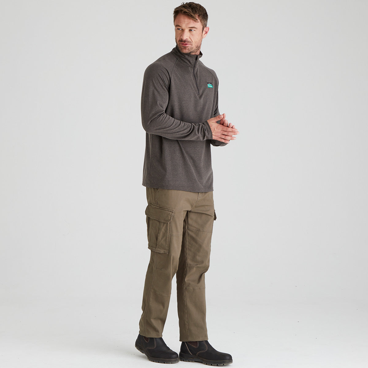 Man wearing a gray long-sleeve shirt and brown cargo pants on a white background