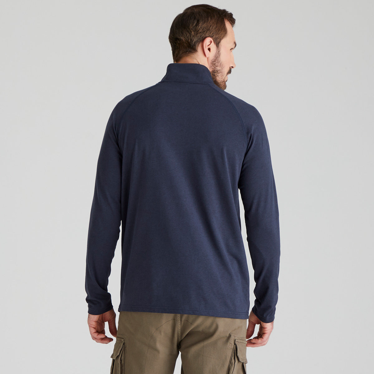 back view of man wearing a navy long-sleeve shirt on a light grey background