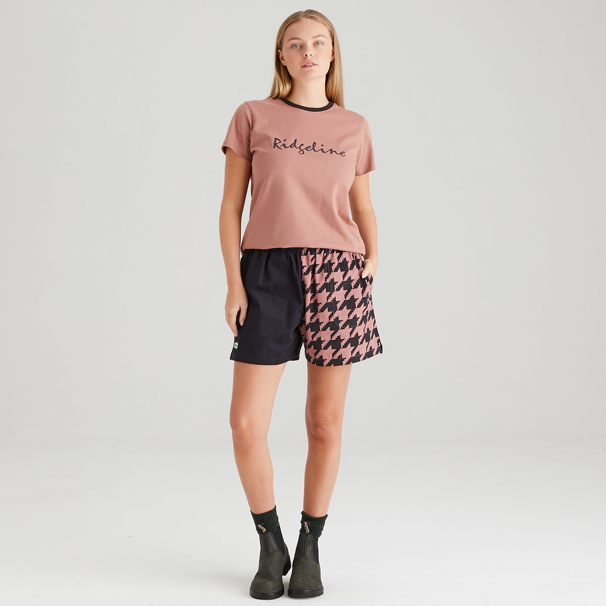 Woman wearing a pink t-shirt and patterned shorts on a white background