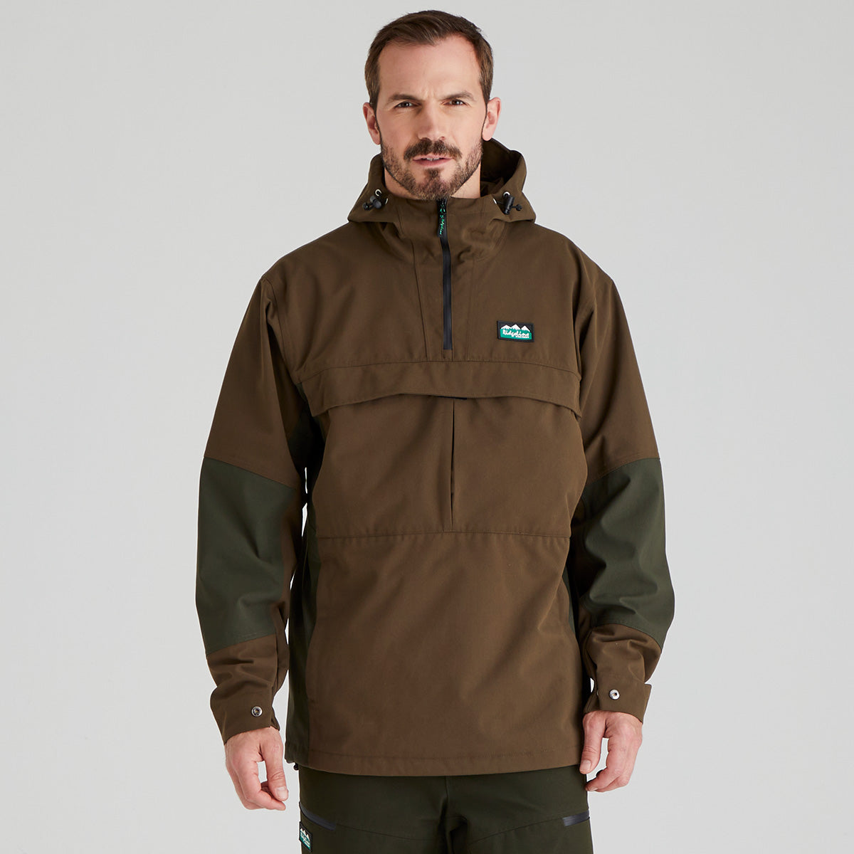 Man wearing a brown and green waterproof jacket with a Ridgeline Clothing logo on a grey background