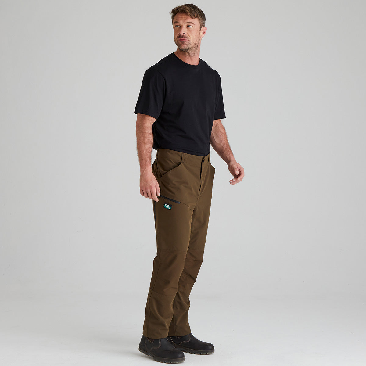 Man wearing brown pants and a black shirt on a gray background