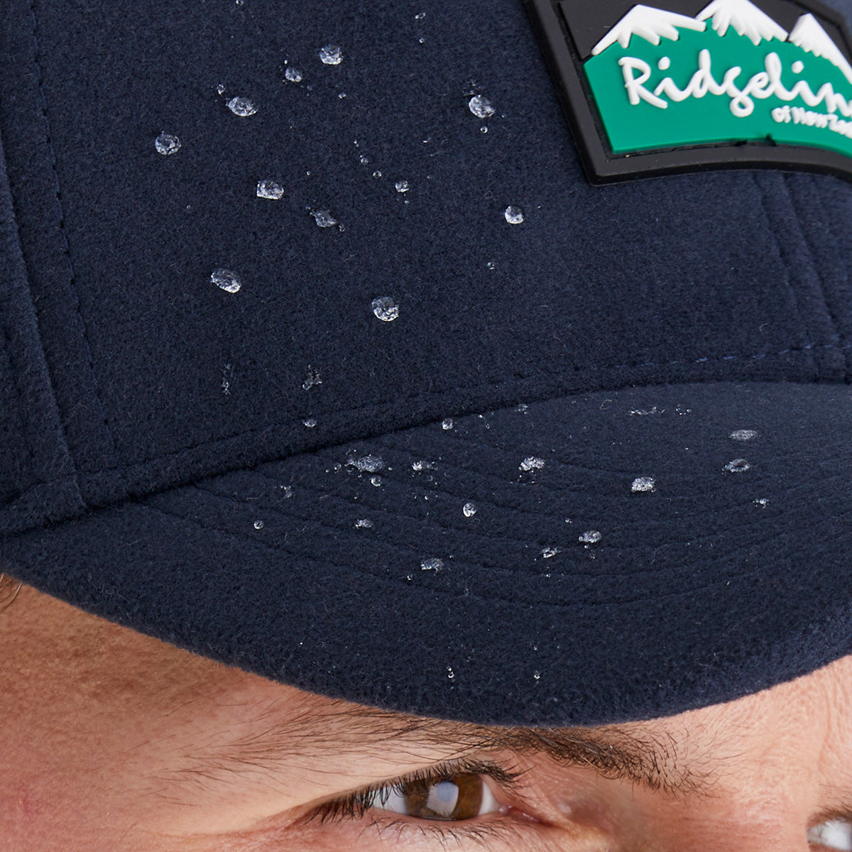 Navy blue cap with a visible Ridgeline Clothing brand logo, close-up view of waterproof feature.