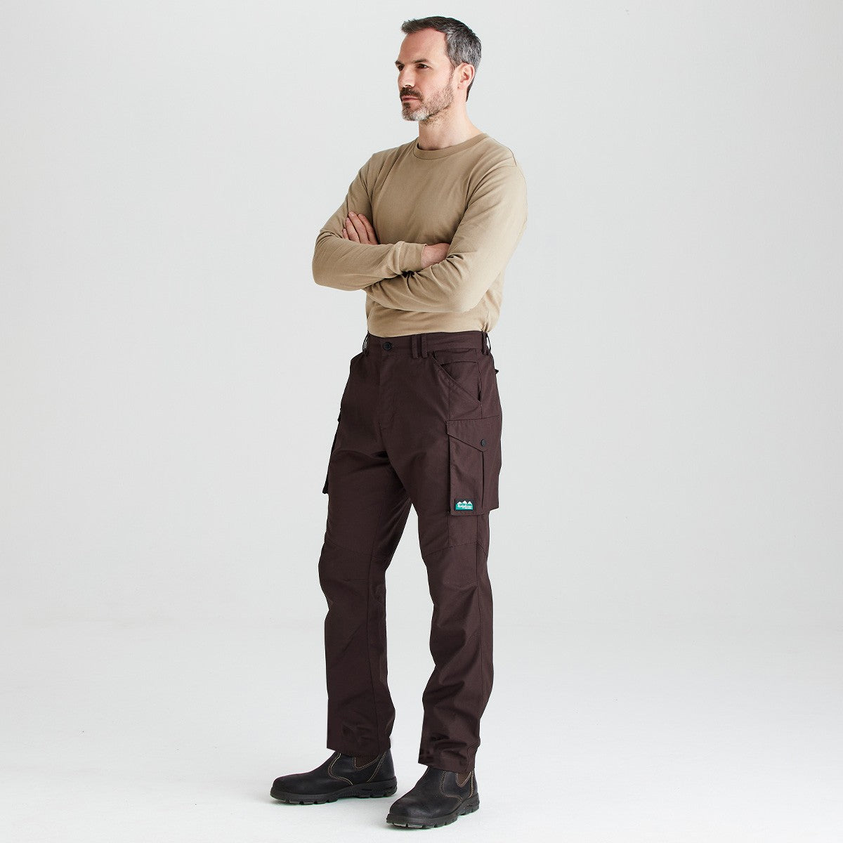 Brown cargo work trousers with utility pockets, angled front-side view worn with black work boots.