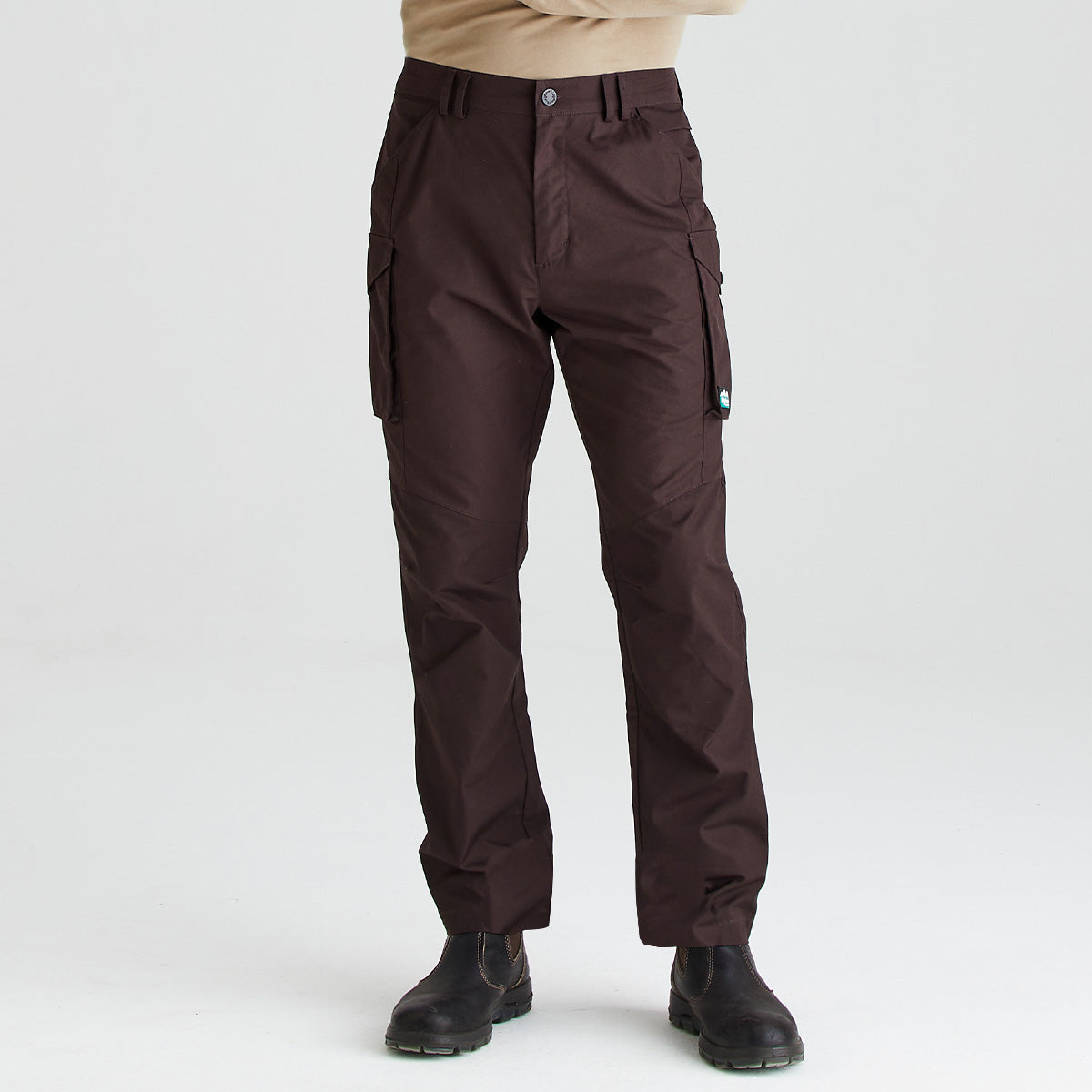 Dark brown cargo pants worn by a model, paired with black boots and a beige top, shown against a plain white studio background.