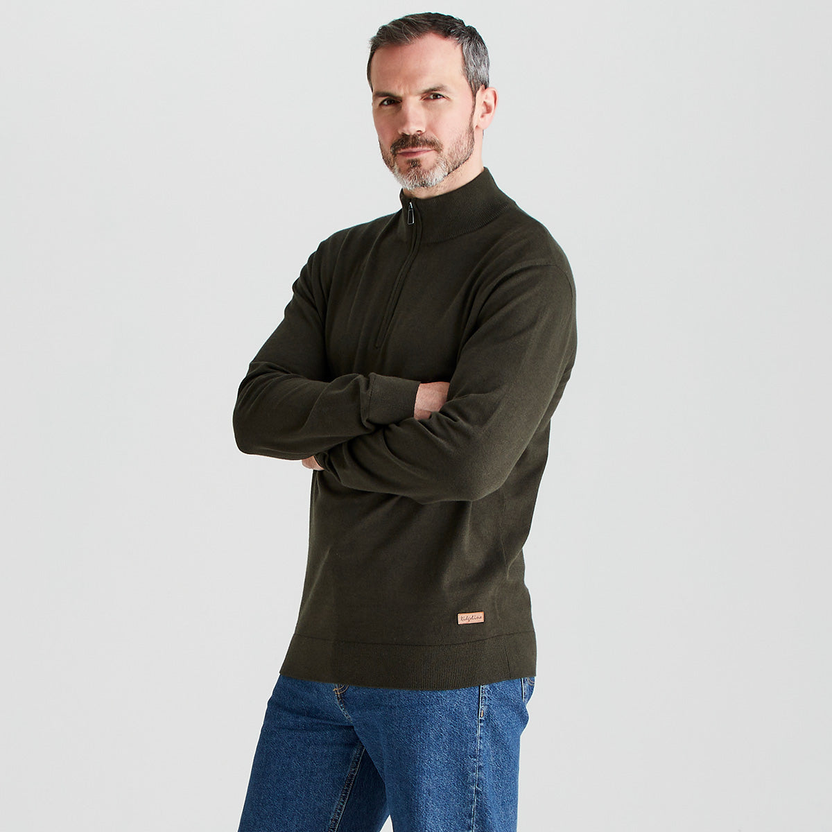 Man wearing a green pullover with a small logo on a light gray background