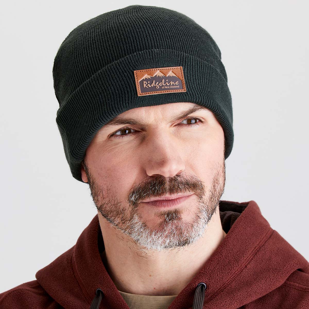 Man wearing a greenish ridgeline beanie in a studio background.
