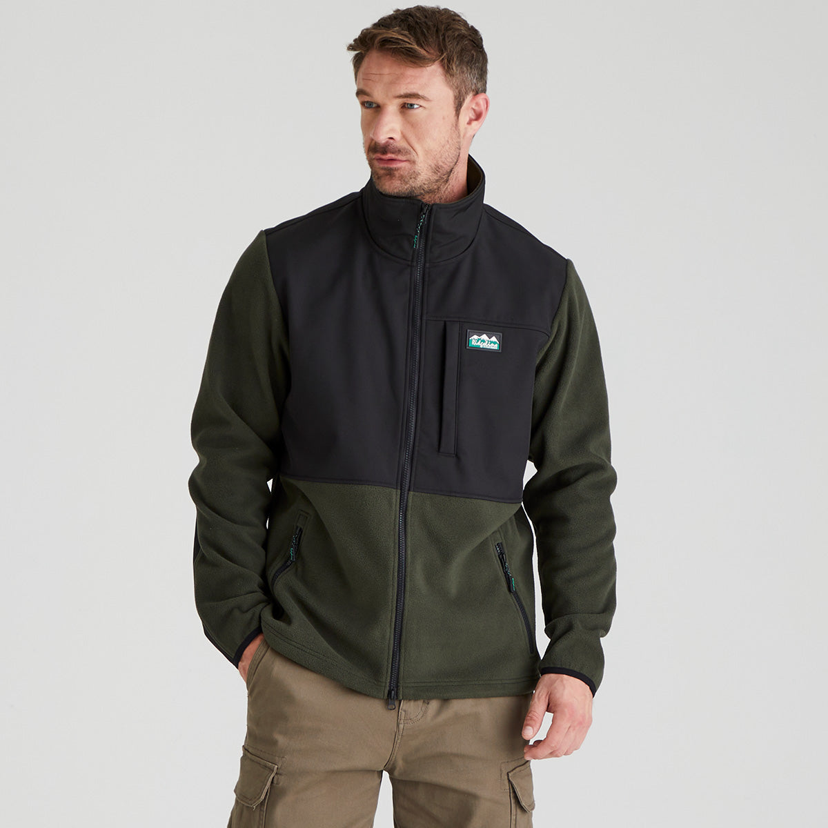 Man wearing a green and black windproof fleece  jacket with a white background