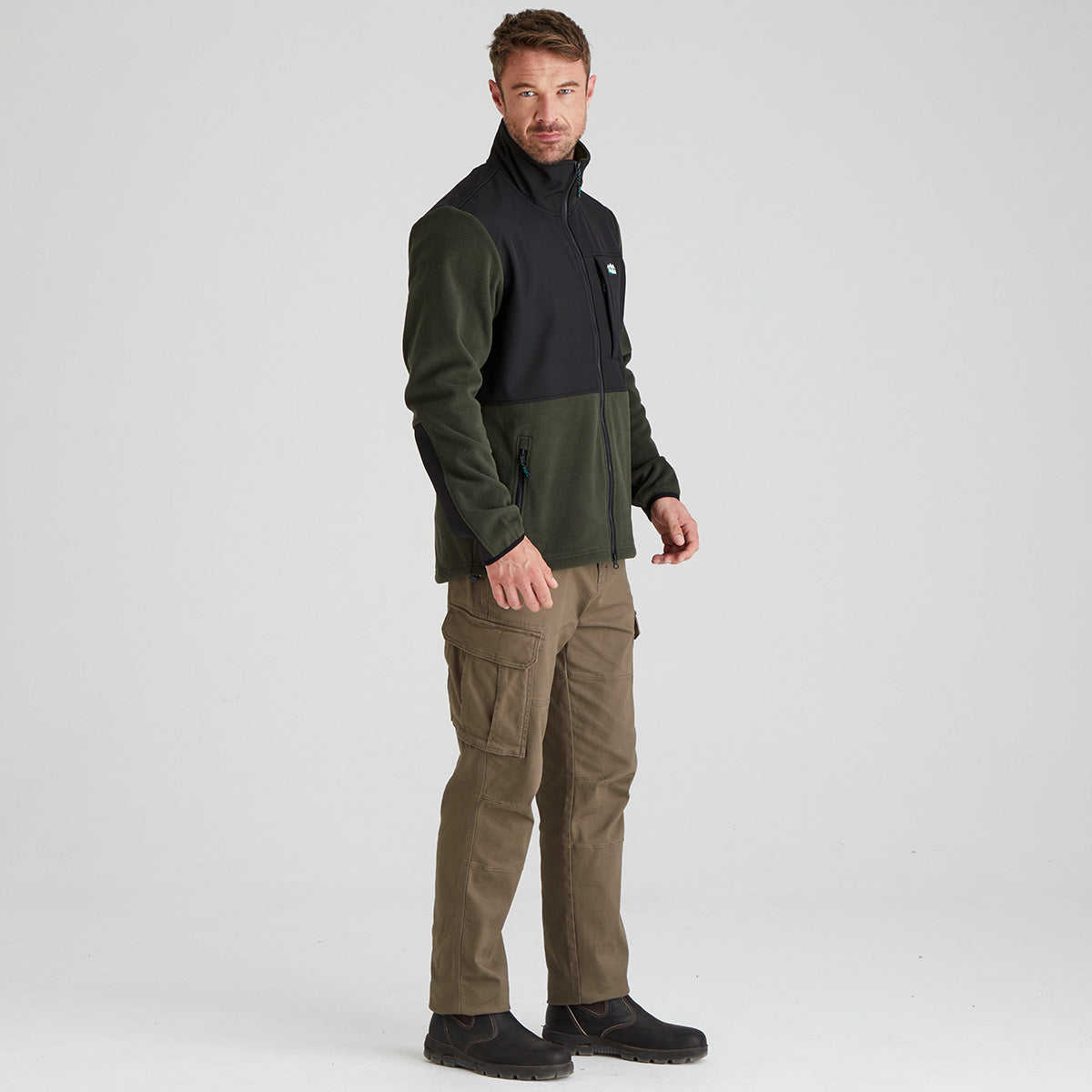 Man wearing a green and black windproof fleece  jacket with a white background