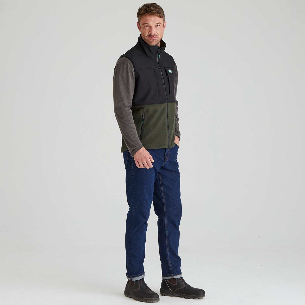 Man wearing a two-tone fleece gilet and blue jeans on a light grey background