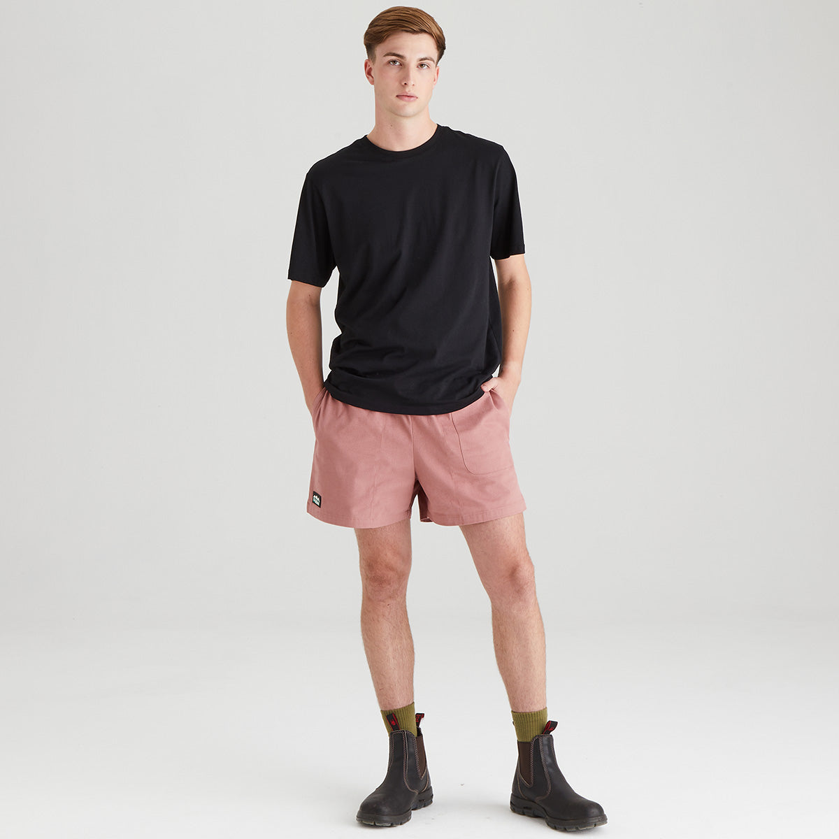 Man wearing a black t-shirt and pink shorts on a white background