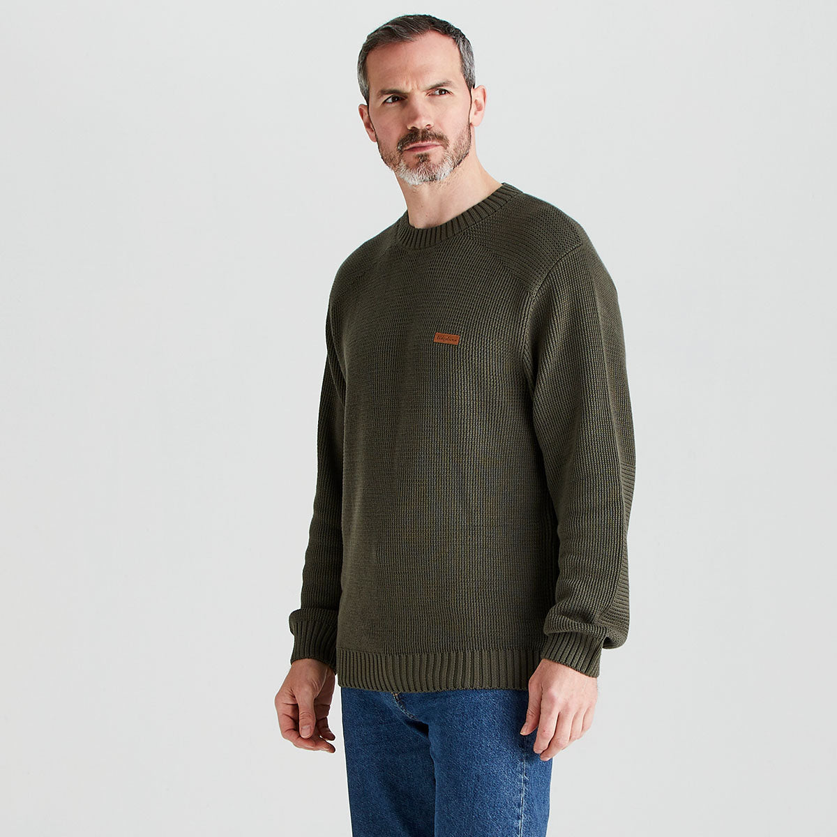 Man wearing a green sweater with a small logo on a light gray background