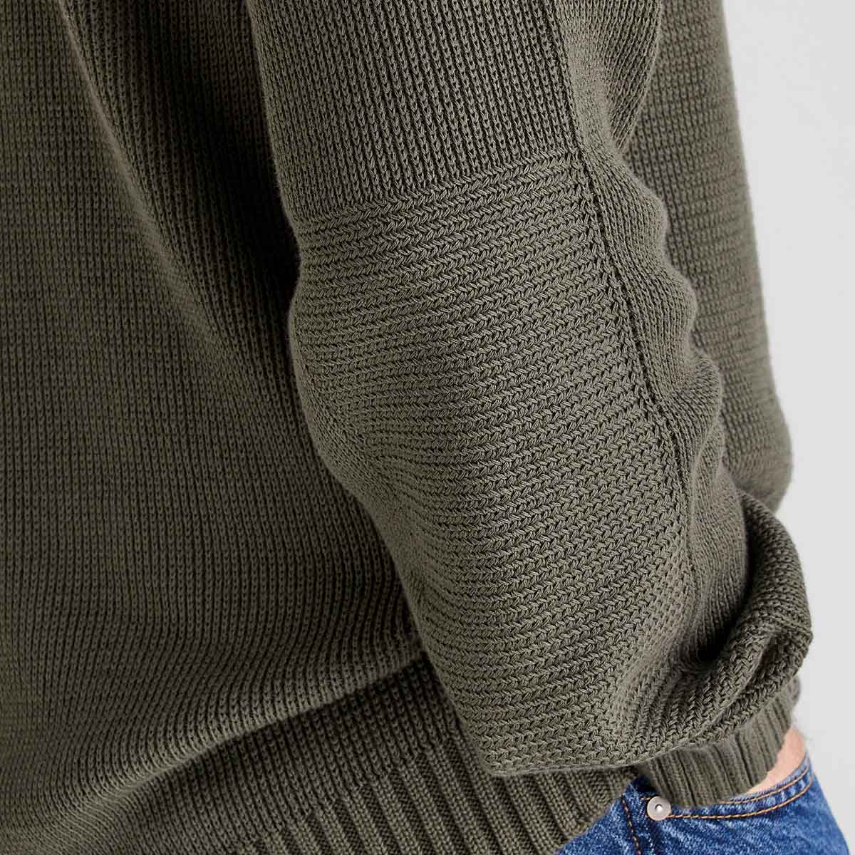 Close-up of a green knitted sweater sleeve on a white background