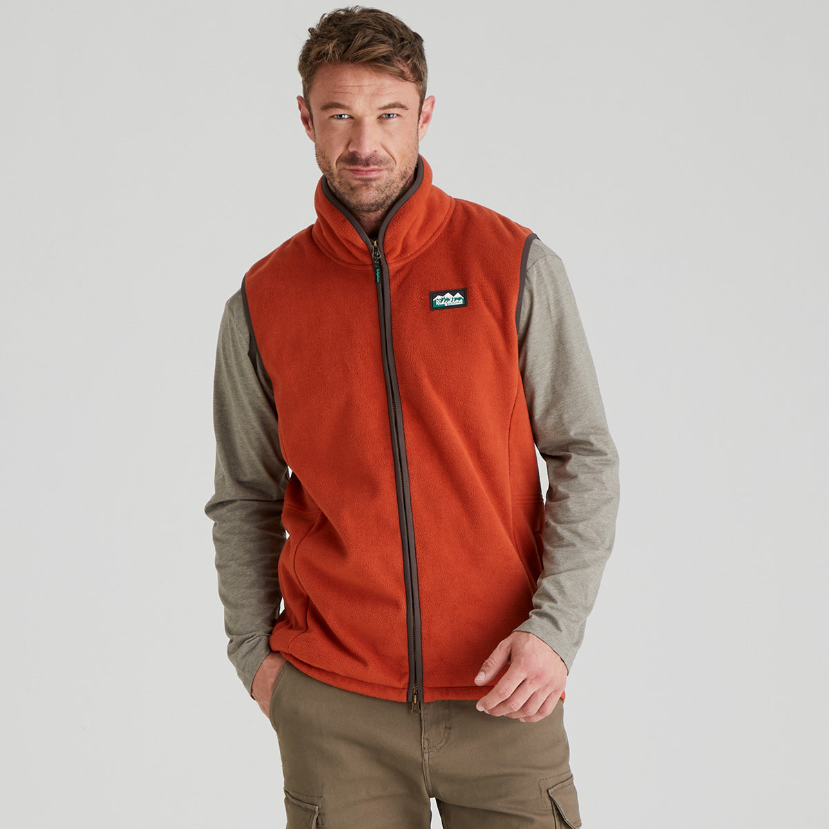 Man wearing an orange windproof fleece vest with a brand logo on a grey background