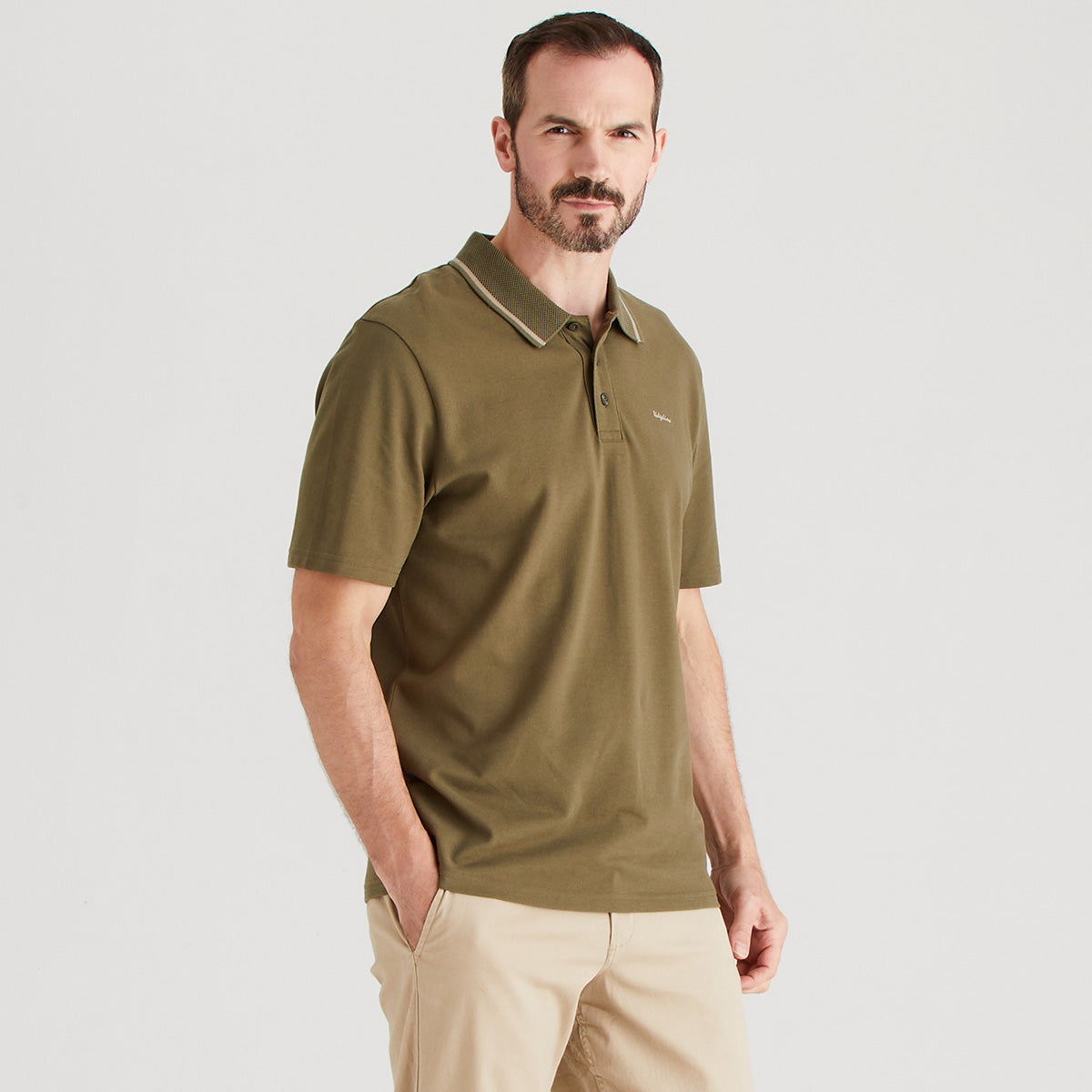 Man wearing a green polo shirt on a light gray background