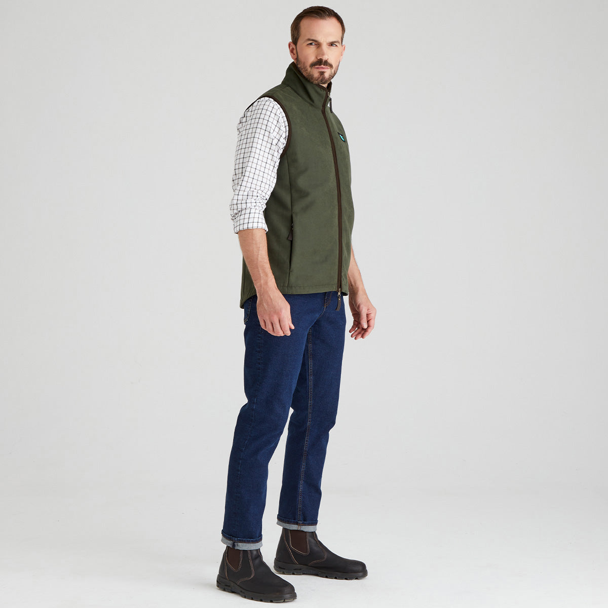 Man wearing Green windproof gilet with checked shirt & jeans