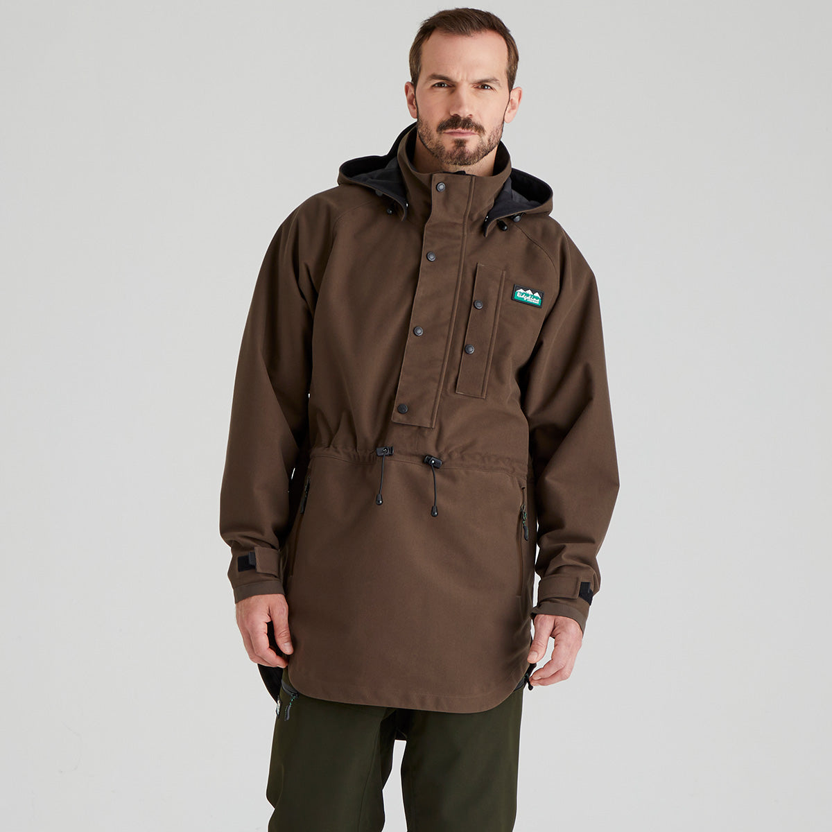 Man wearing a brown waterproof jacket with a visible Ridgeline Clothing brand logo on a grey background