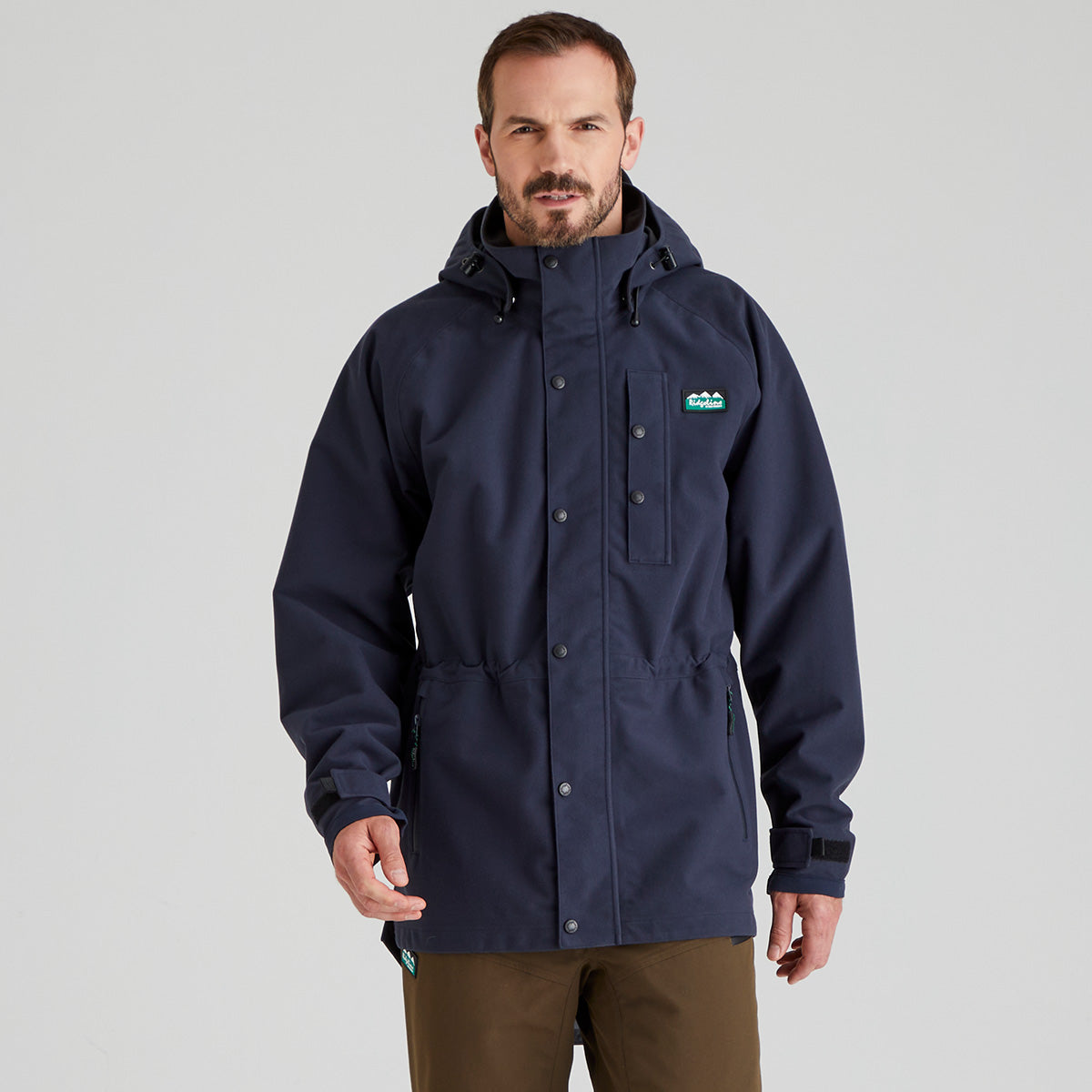 Man wearing a navy blue waterproof jacket with a Ridgeline Clothing brand logo on a grey background
