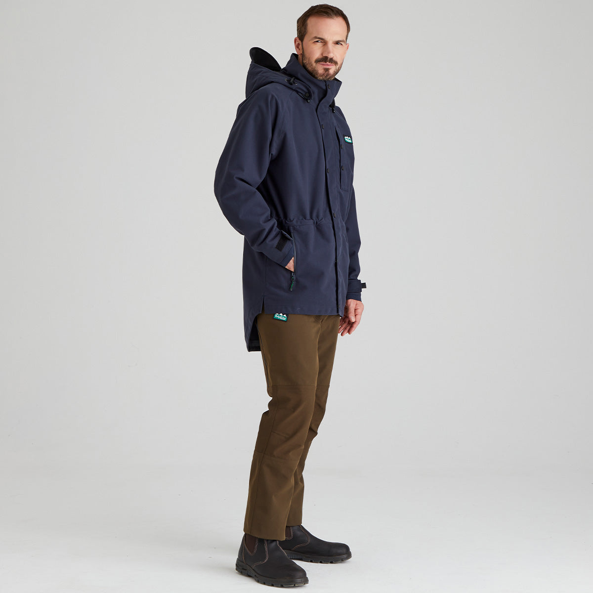 Man wearing a navy blue waterproof jacket with a Ridgeline Clothing brand logo on a light grey background