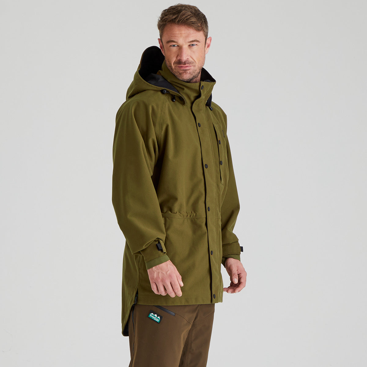 Man wearing a brown waterproof jacket on a light grey background