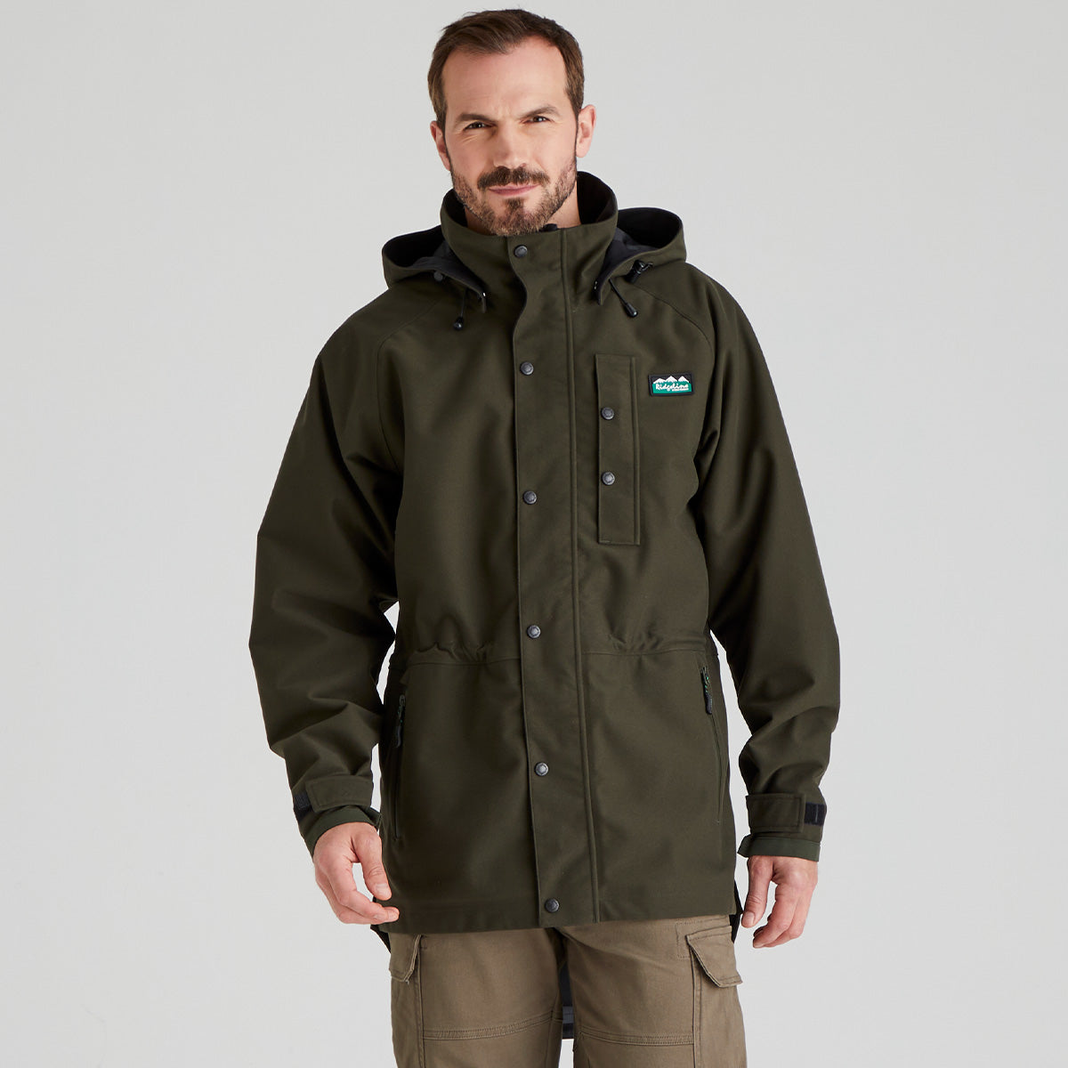 Man wearing a green waterproof jacket with a Ridgeline Clothing brand logo on a grey background
