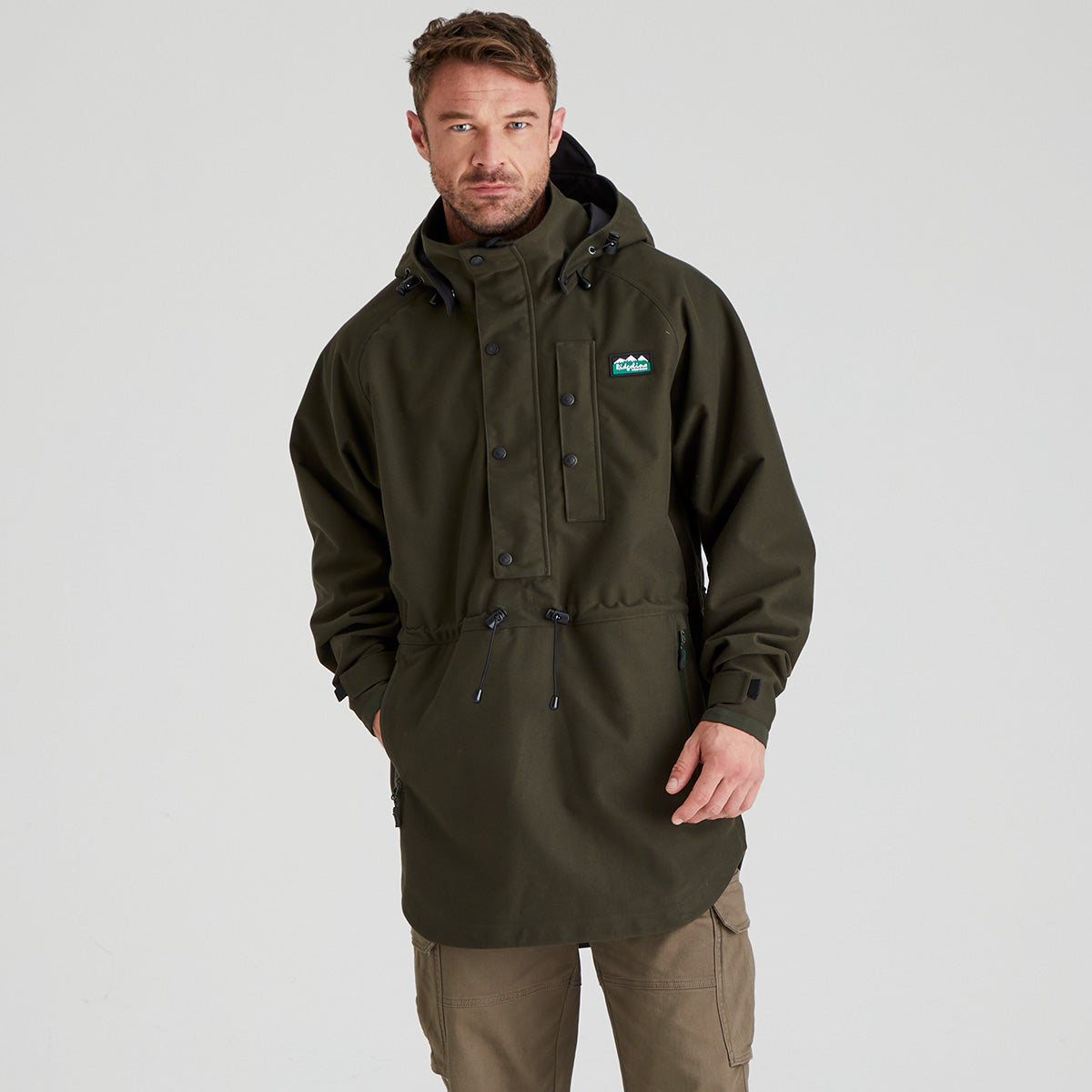 Man wearing a green waterproof jacket with a Ridgeline Clothing brand logo on a grey background