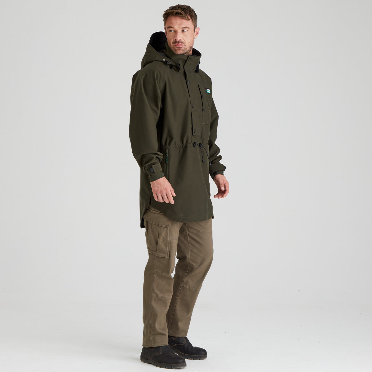 Man wearing a green raincoat and pants on a white background