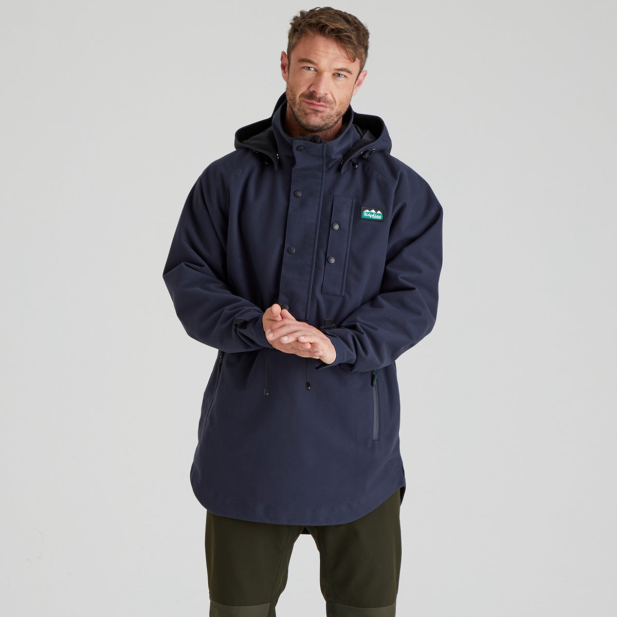 Man wearing a navy blue waterproof jacket with a ridgeline clothing brand logo on a light grey background