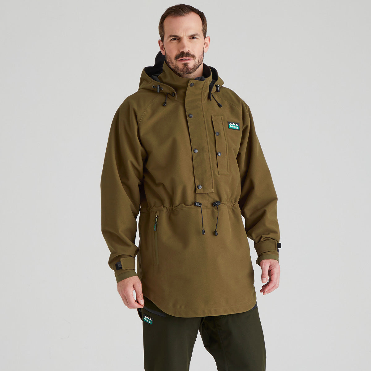 Man wearing a green jacket with a brand logo on a grey background