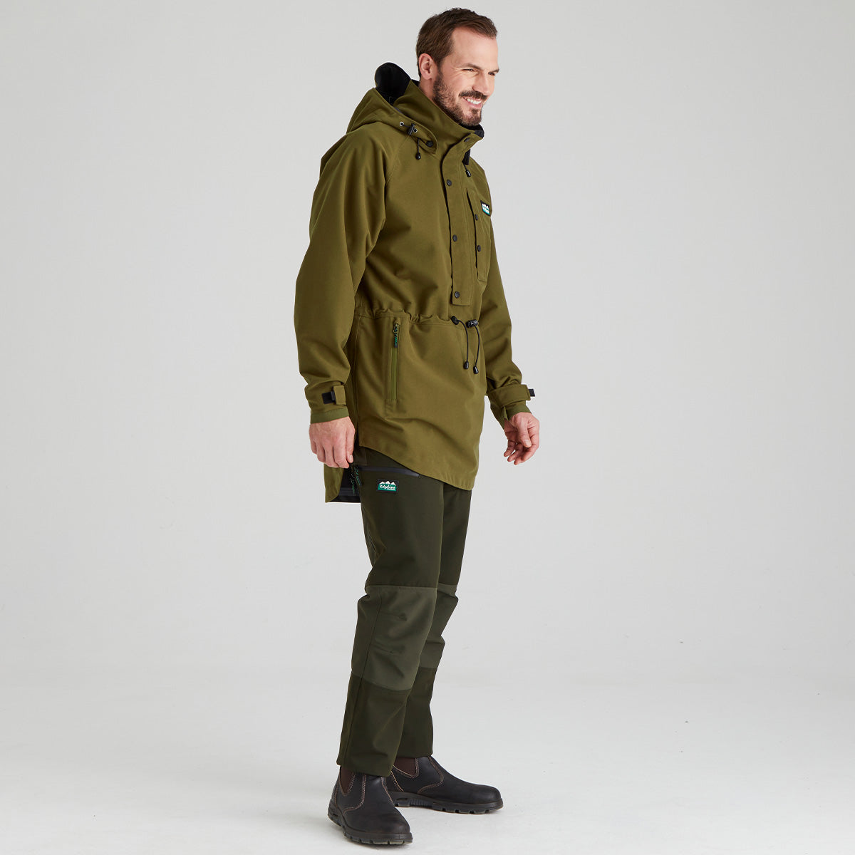 Man wearing a brown waterproof jacket and pants on a white background