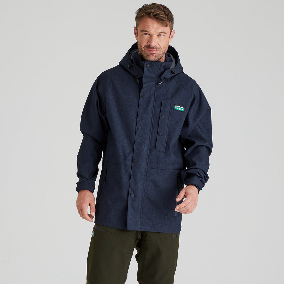 Man wearing a navy waterproof jacket with a ridgeline clothing brand logo on a grey background