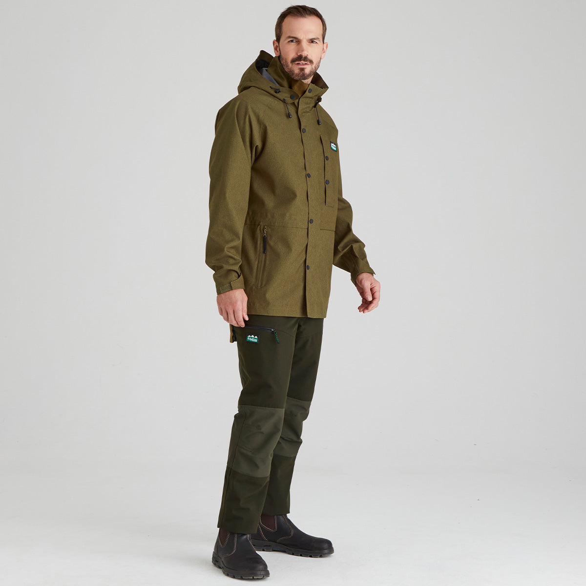 Man wearing a green jacket and dark green trousers on a white background