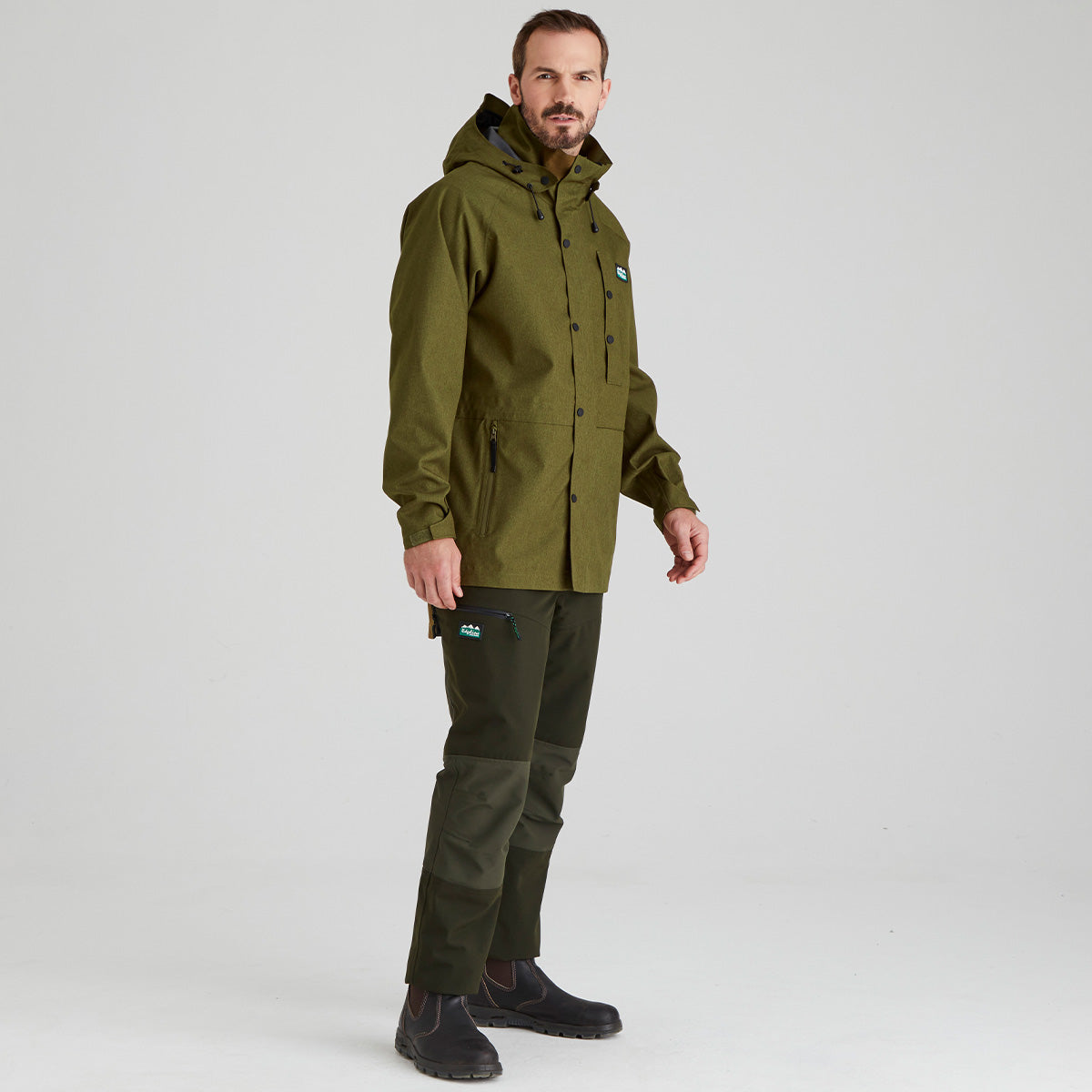 Man wearing a green raincoat and pants on a white background