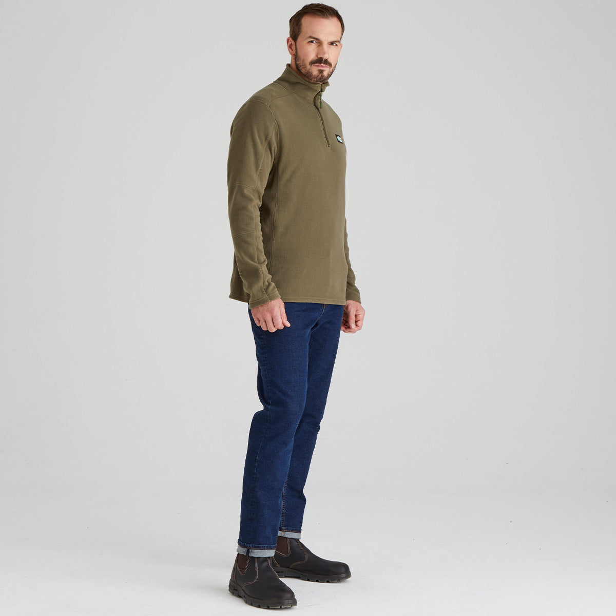 Man wearing green pullover quarter zip fleece with ridgeline clothing logo & jeans