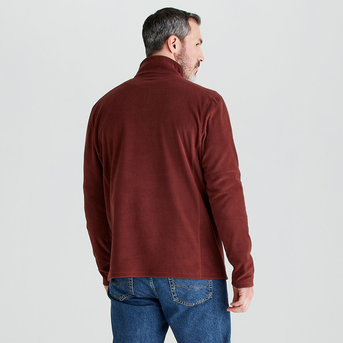man shown wearing a ridgeline fleece in red and blue jeans