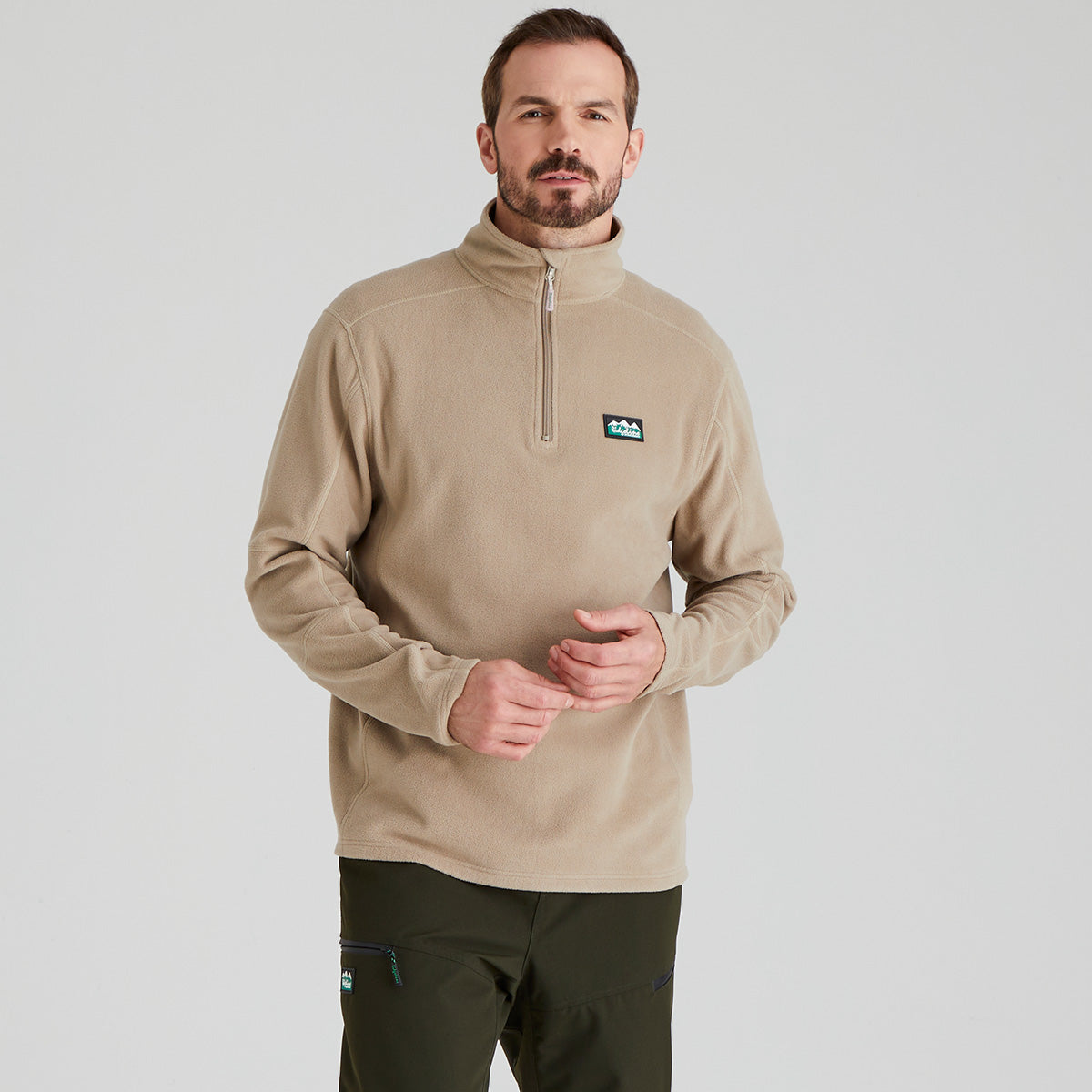 Man wearing a beige pullover fleece  with a Ridgeline Clothing brand logo on a light grey background