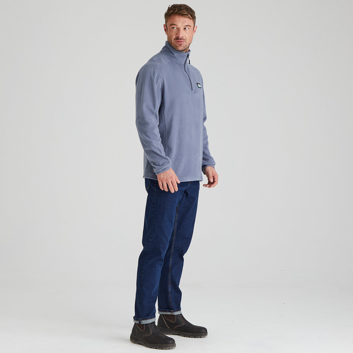 Man wearing a light blue pullover and blue pants on a white background