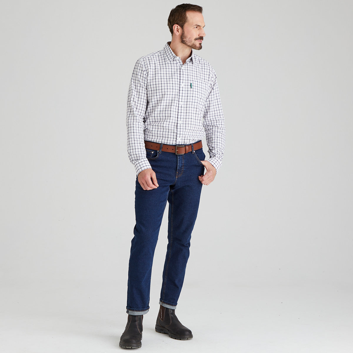 Man wearing a checkered shirt and blue jeans on a light grey background