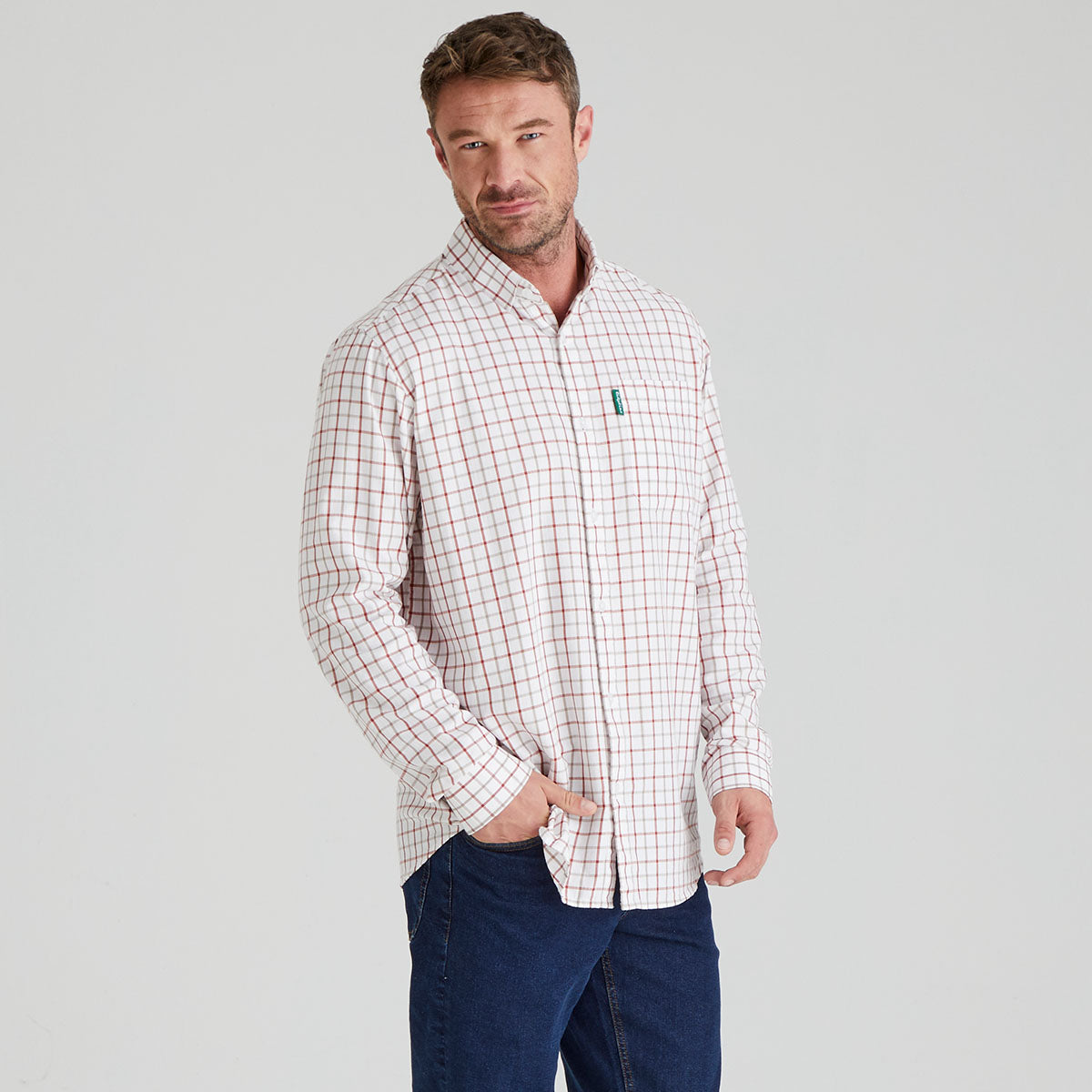 Man wearing a checkered shirt with a visible brand logo on a grey background
