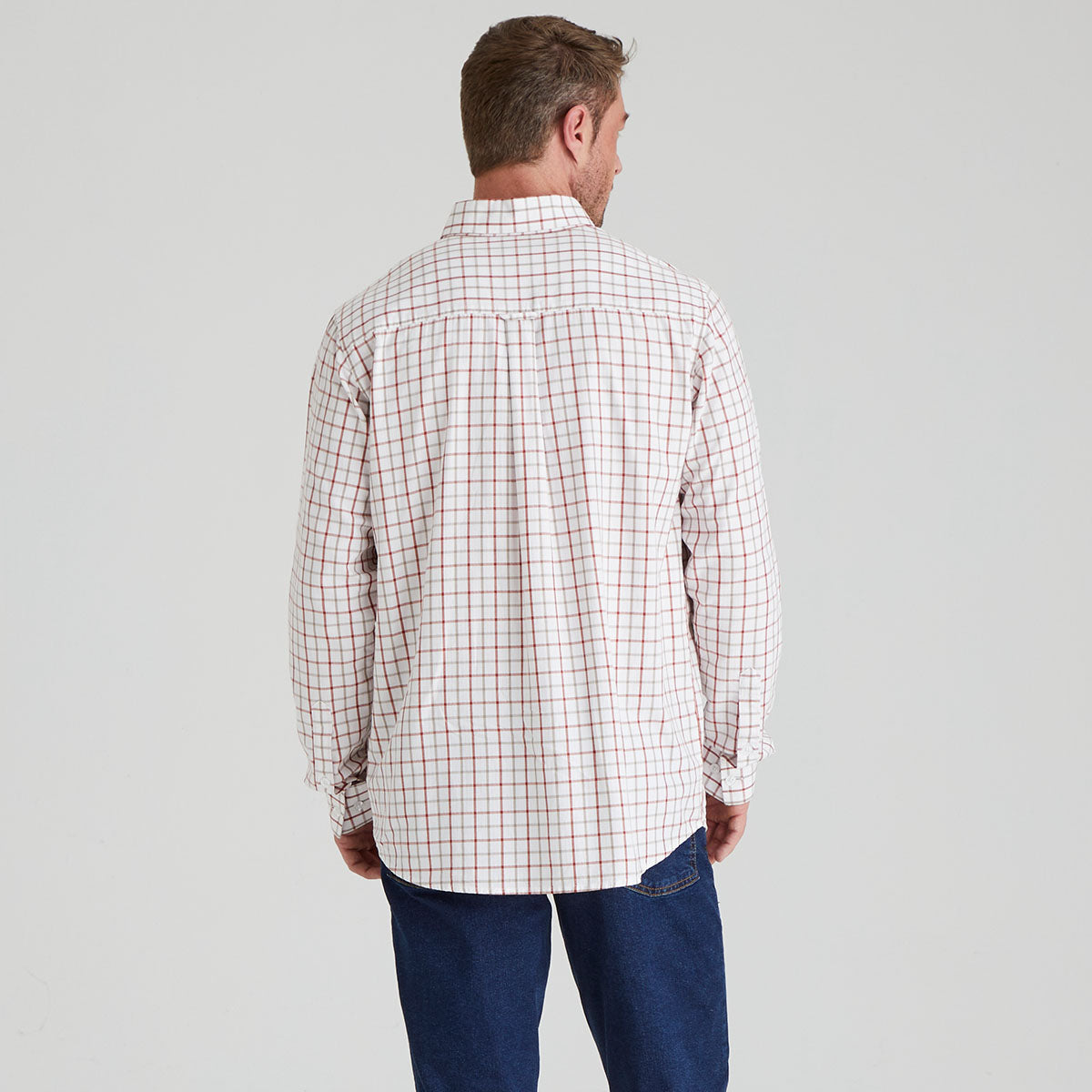 Man wearing a plaid shirt and jeans on a grey background