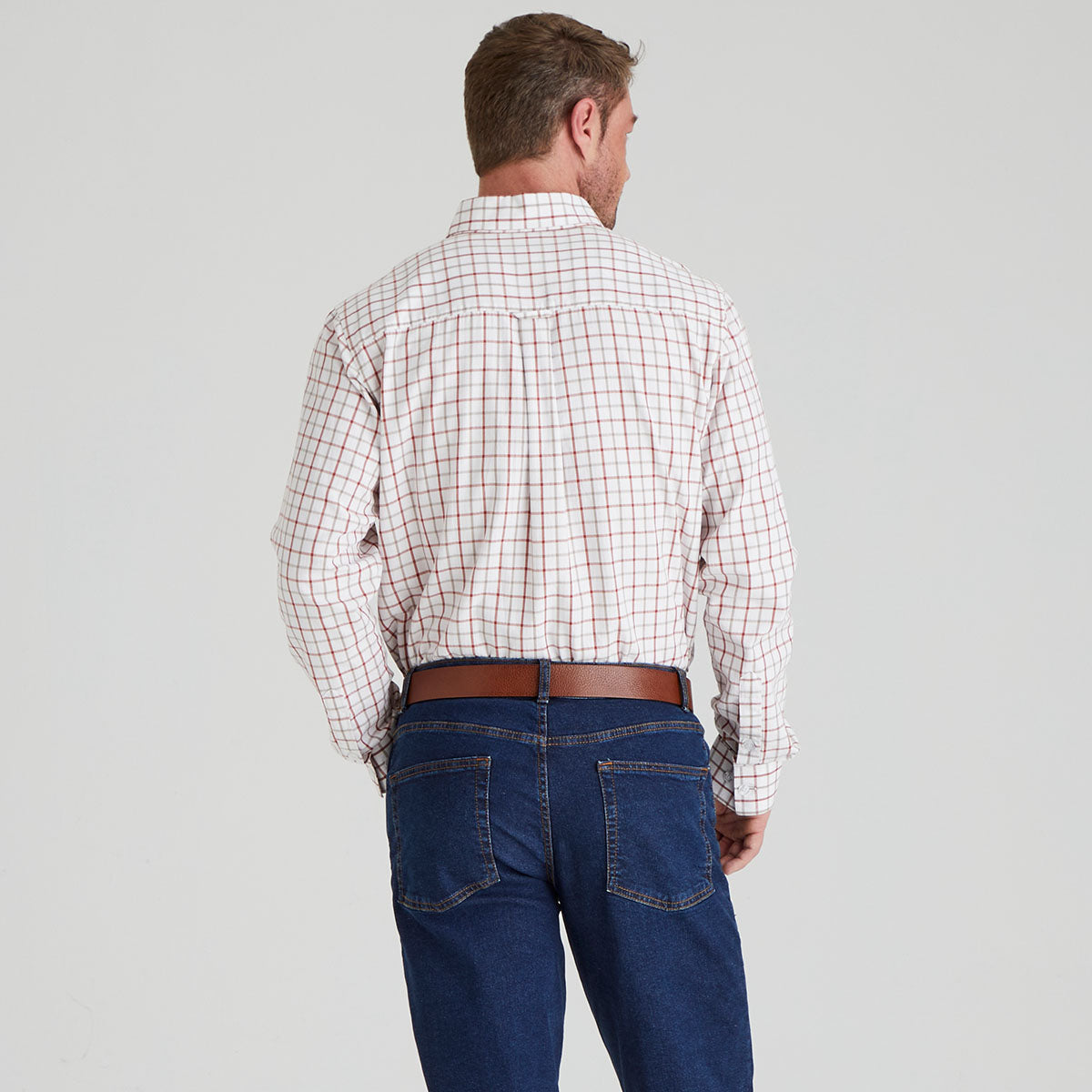 Man wearing a plaid shirt and blue jeans on a grey background