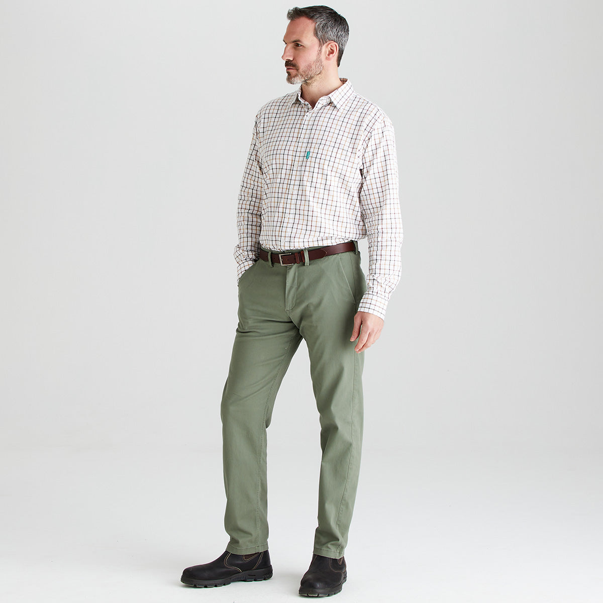 Man wearing a checkered shirt and green pants on a white background