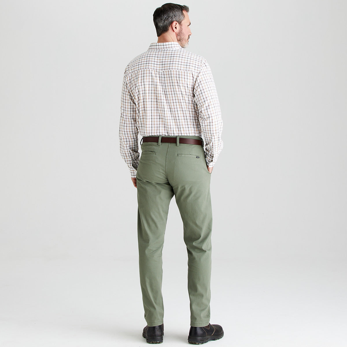 Man wearing green pants and a checkered shirt on a light gray background
