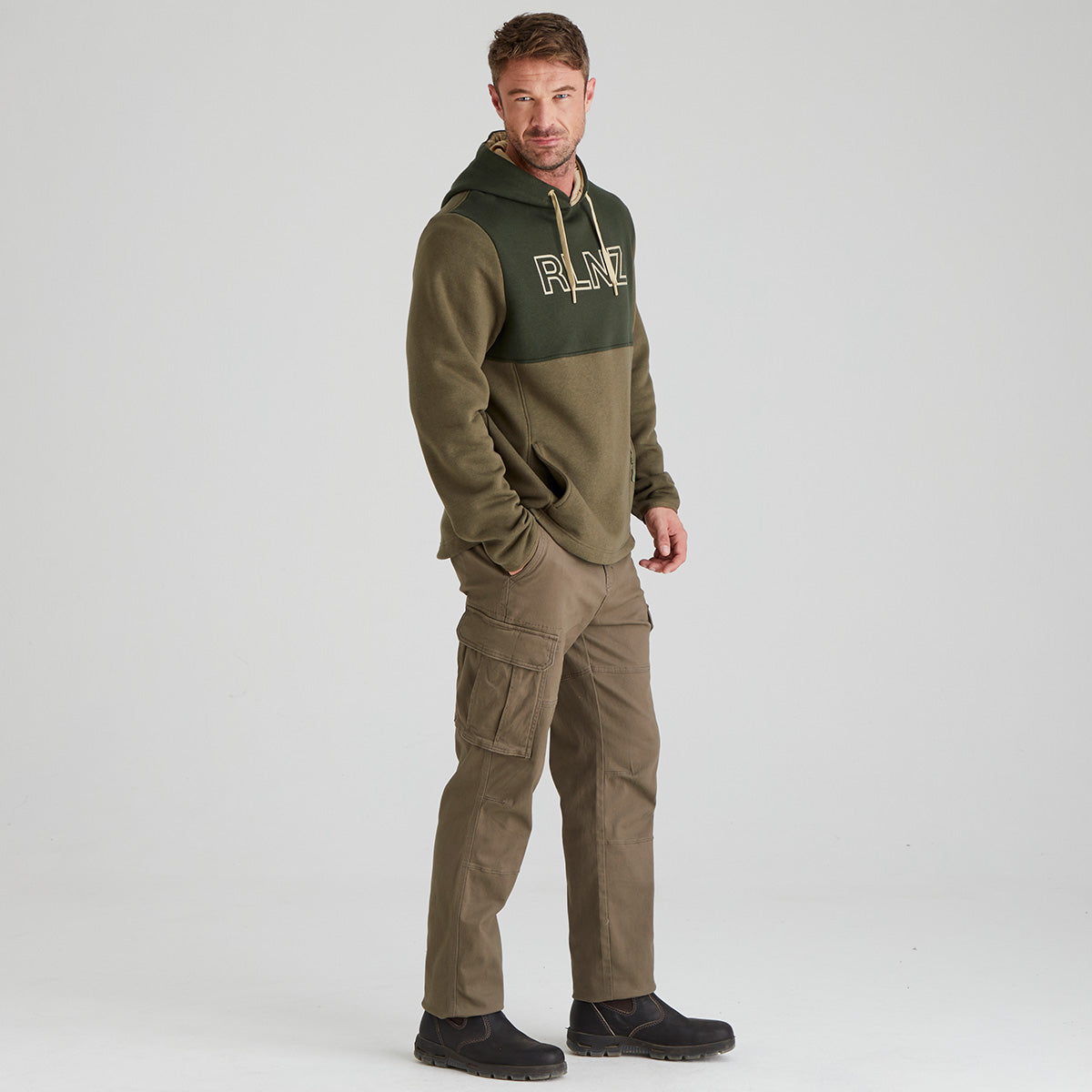 Man wearing a green and brown hoodie with cargo pants on a white background