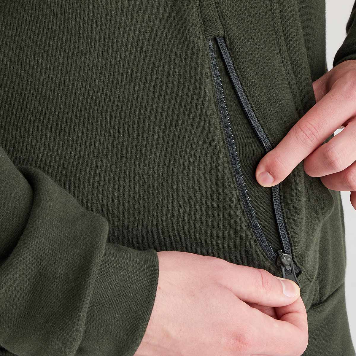 Close-up of a person adjusting the zipper on a green jacket.