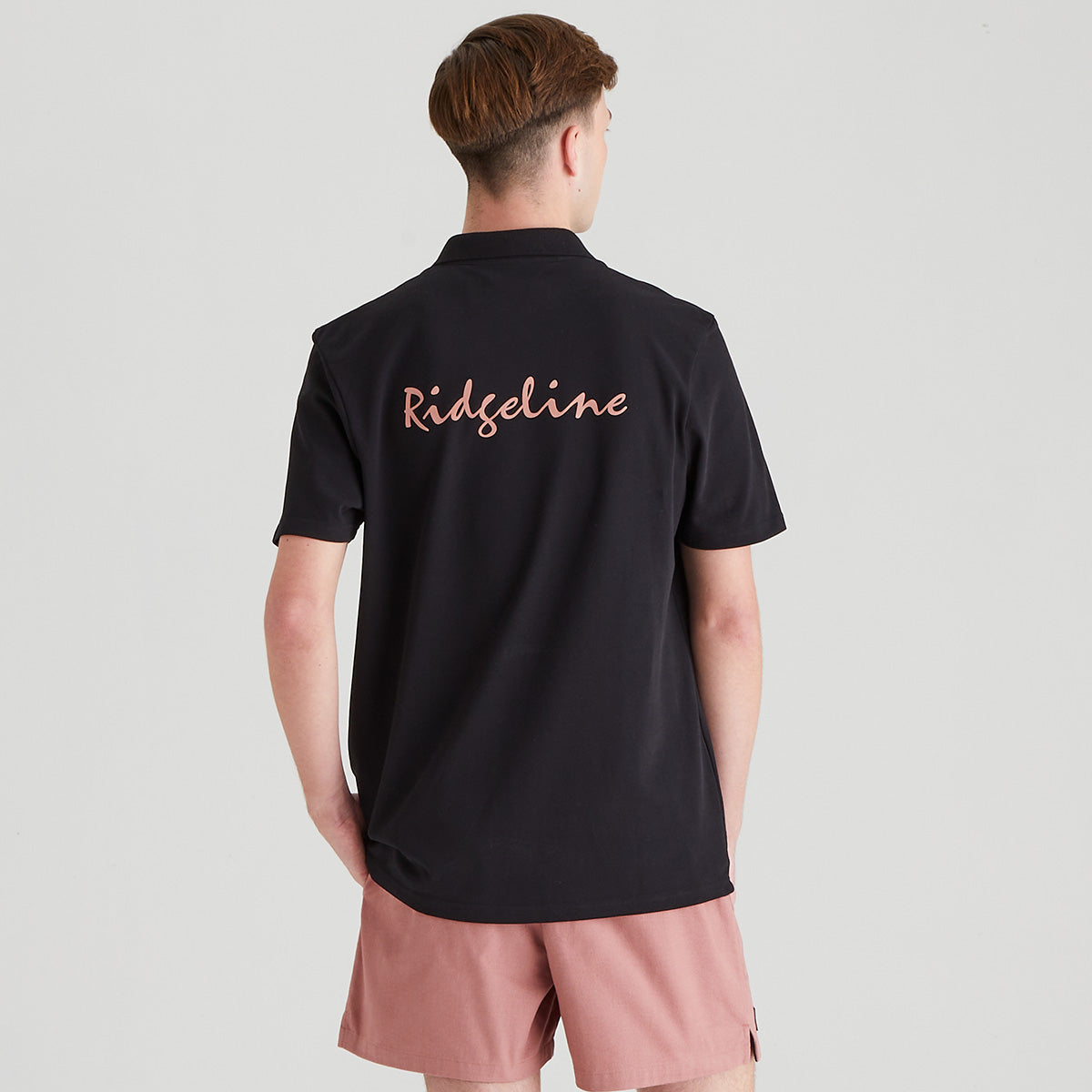 Person wearing a black shirt with 'Ridgeline' text on the back, standing against a light gray background