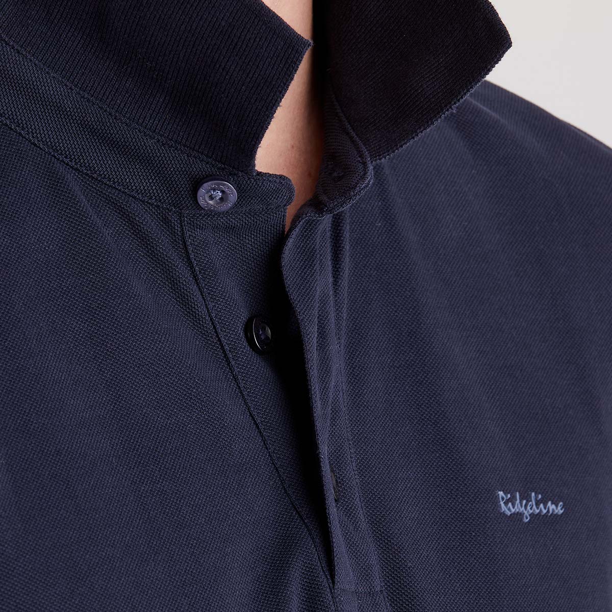 Navy blue polo shirt with collar and brand logo on a neutral background