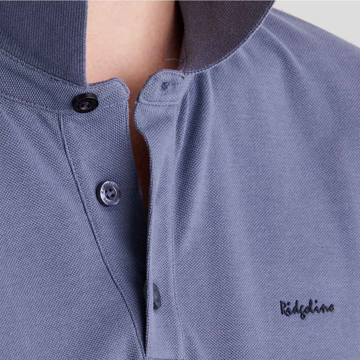 Close-up of a blue polo shirt with brand logo on a light gray background