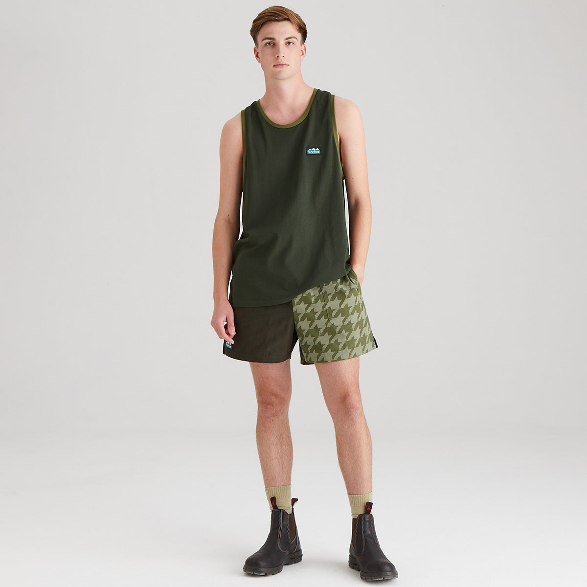 Person wearing a green tank top and patterned shorts on a white background